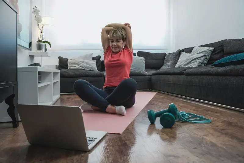 Frau trainiert Zumba online zu Hause vor dem Laptop