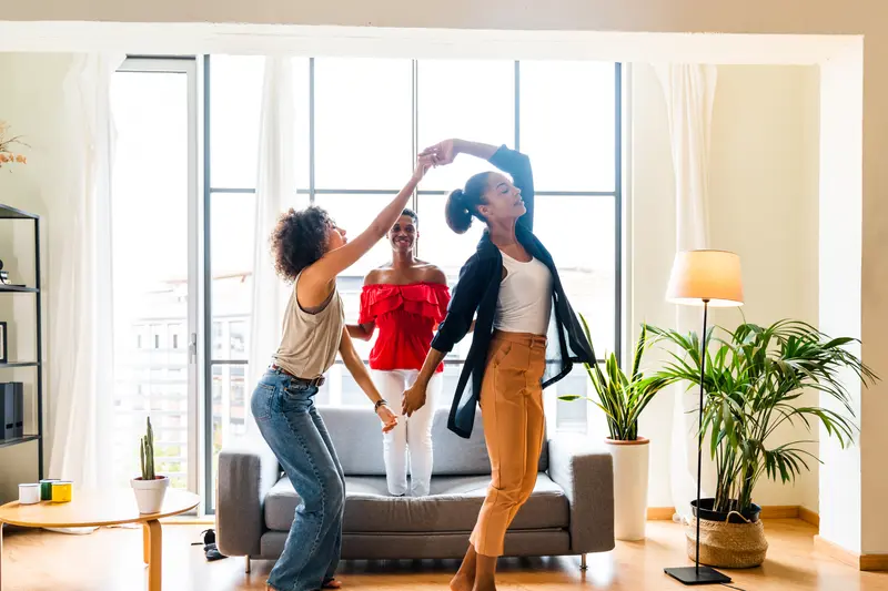 Frauen tanzen zusammen im Wohnzimmer